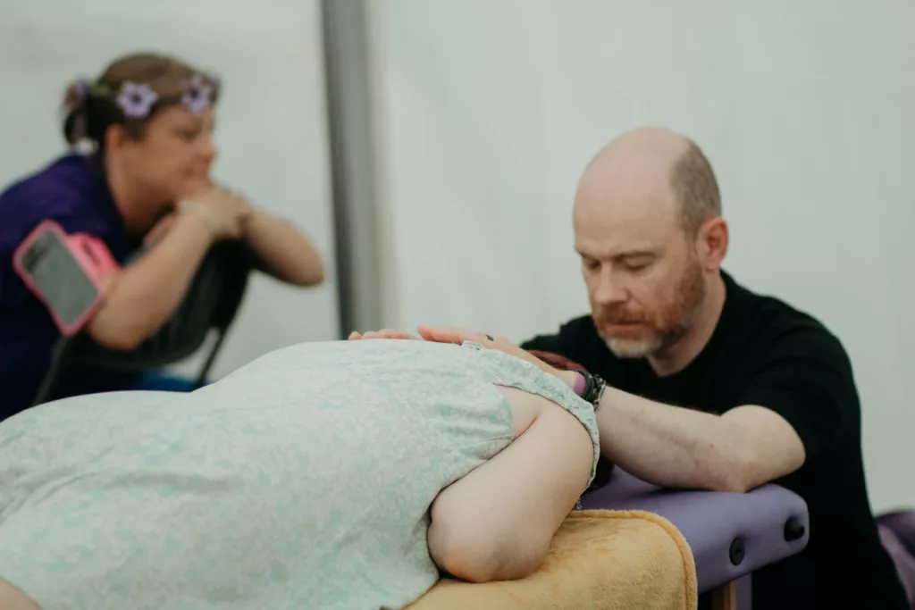 a man with his eyes closed and hands placed across a persons back providing a massage